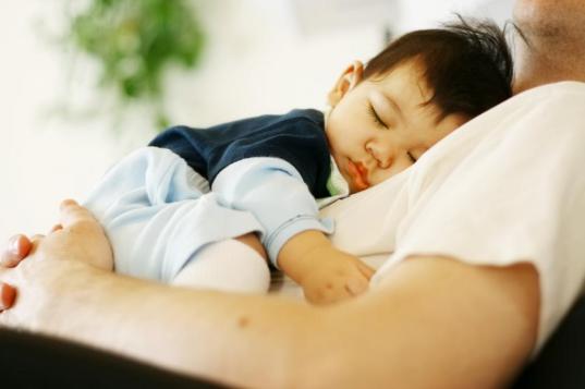 Biracial baby boy asleep on father's chest